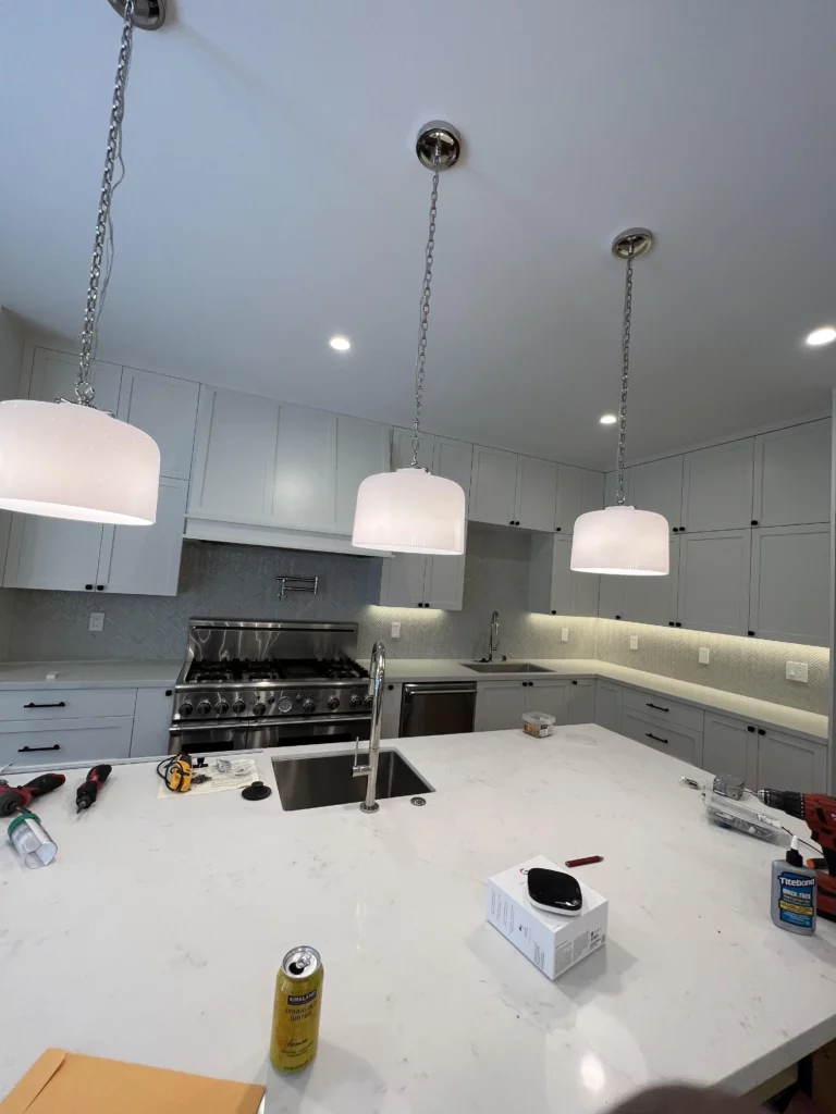 Local electrician hanging pendent lights in a kitchen.